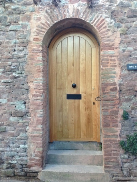 Arched oak door in a stone porch